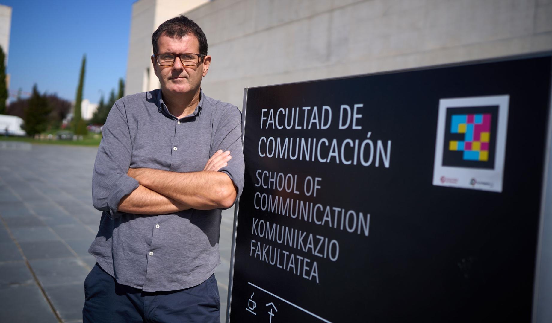 Pablo Echart se apoya en un cartel junto a la Facultad de Comunicación de la Universidad de Navarra.