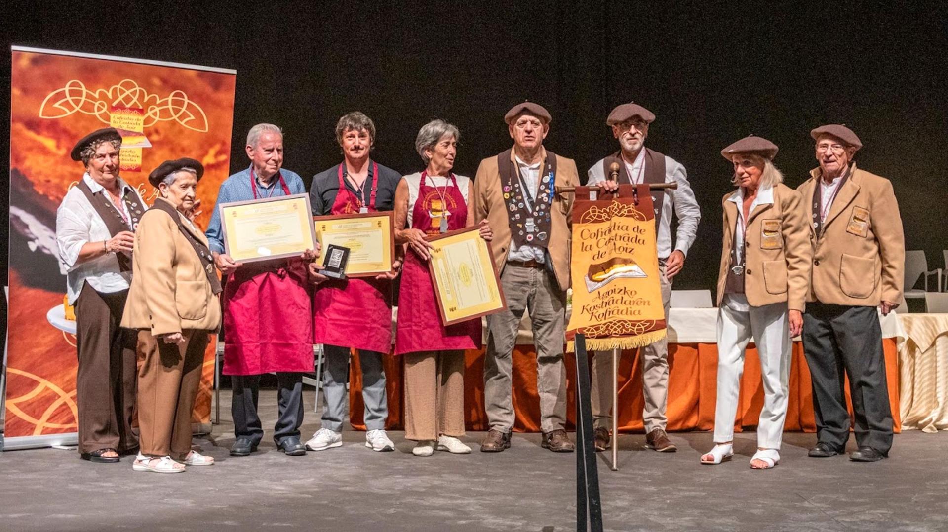 En el centro, con mandarra roja, los homenajeados. Desde la izda.: Josetxo Paternáin, Iñaki Ardanaz y Tere Leache. Los arropan miembros de la Cofradía de la Costrada de Aoiz