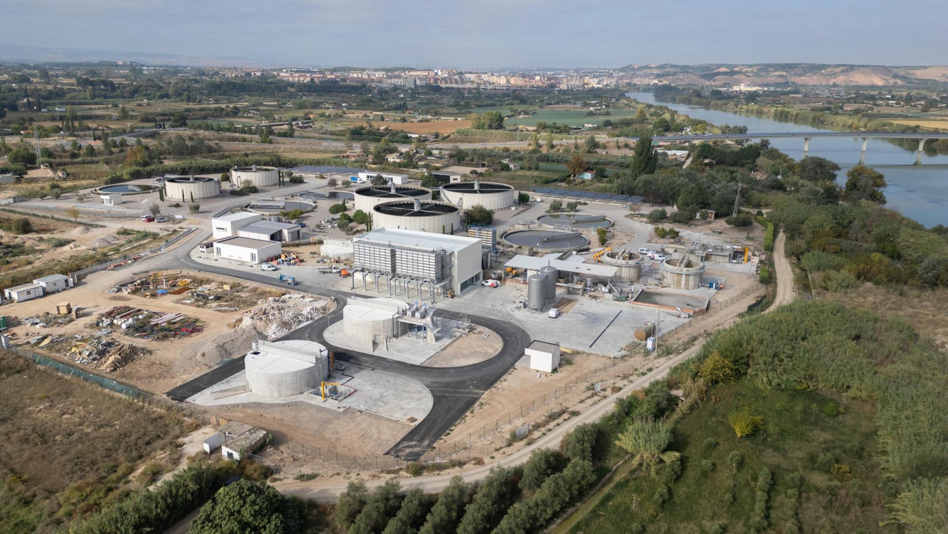 Imagen de la depuradora de aguas residuales de Tudela, con el casco urbano de la ciudad al fondo, y el cauce del río Ebro a la derecha