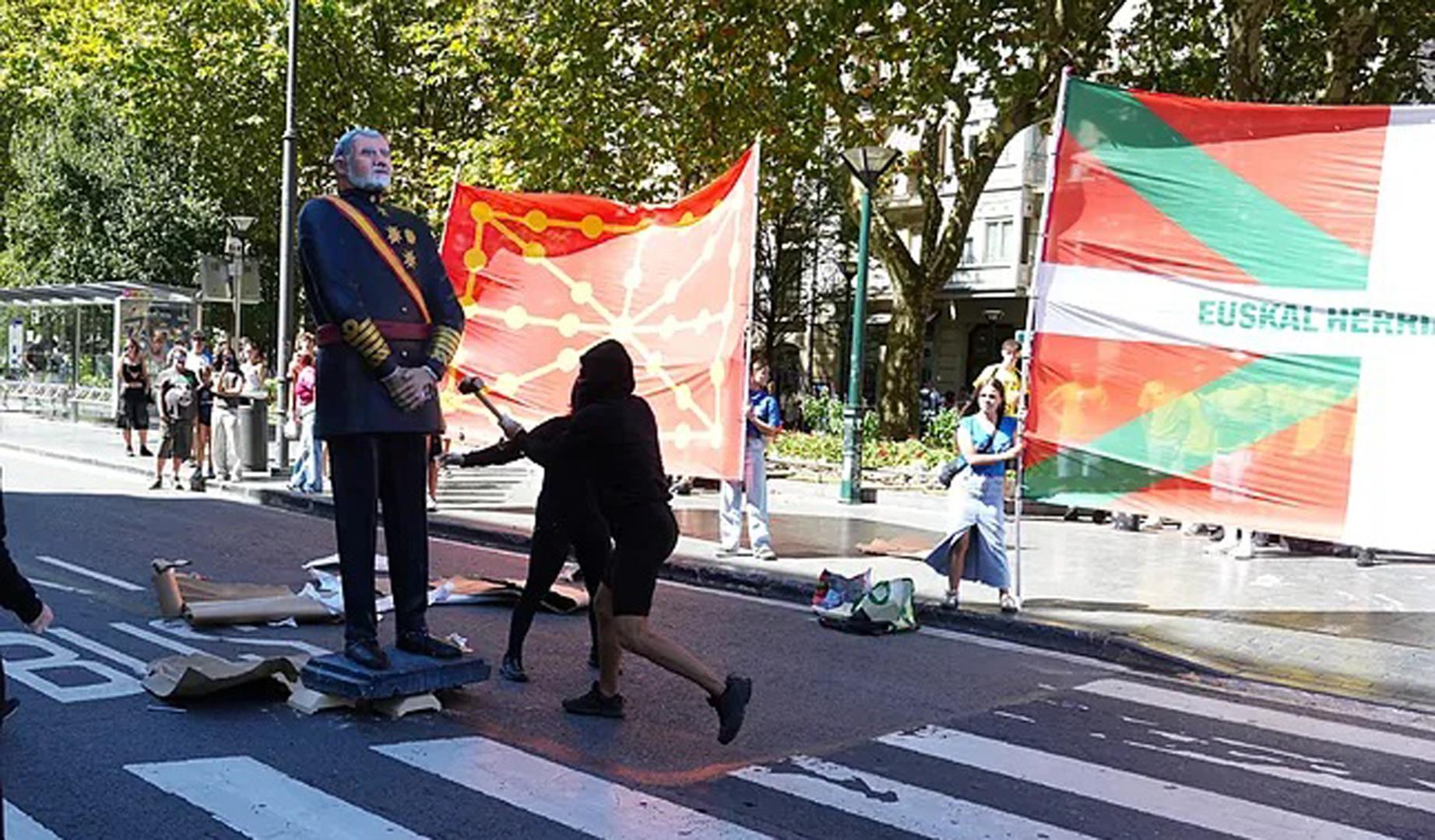 Varios manifestantes encapuchados derriban una estatua del Rey Felipe VI