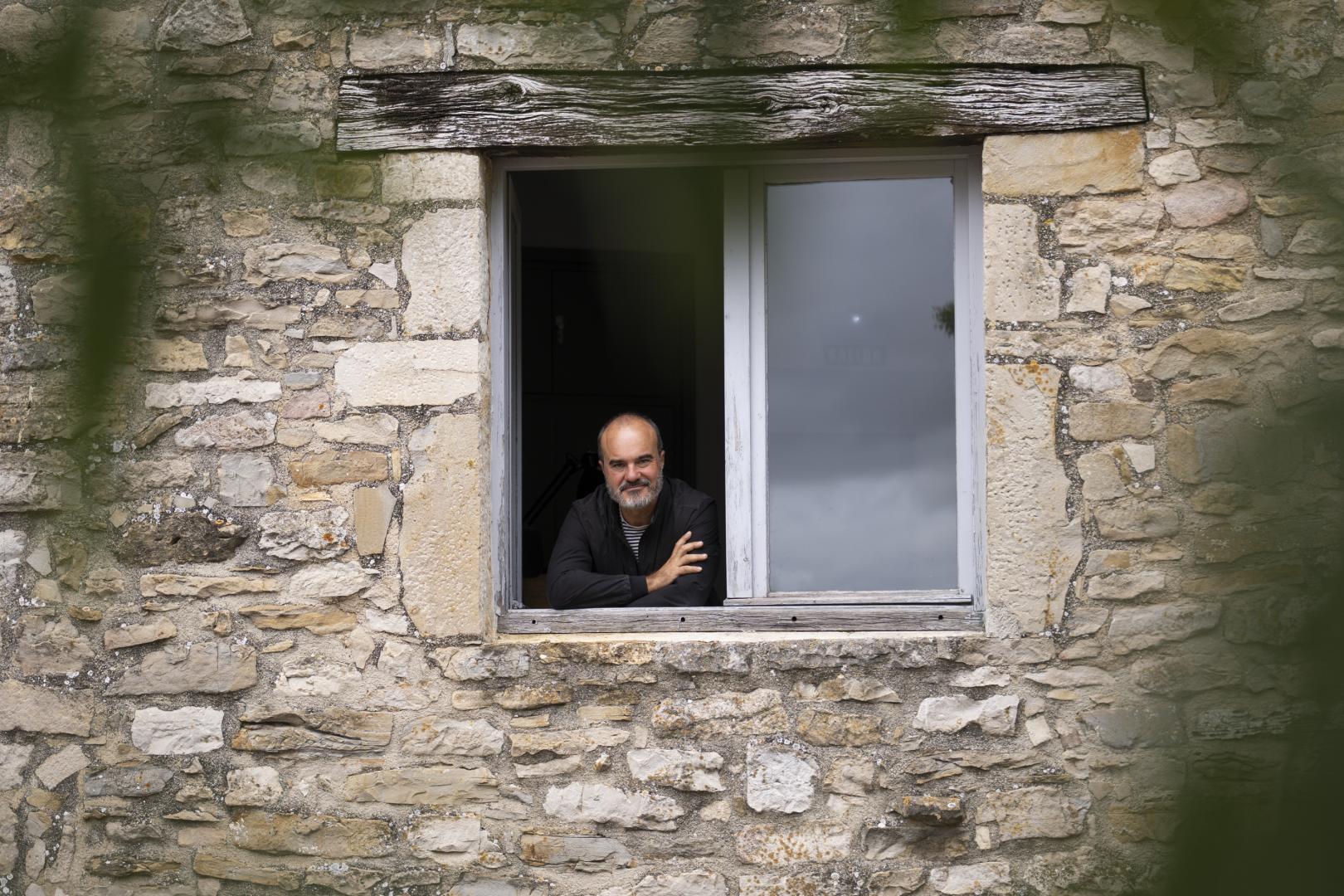Oskar Alegria se asoma a la ventana del dormitorio de Jorge Oteiza en Alzuza, desde la que el escultor veía el fresno (en primer plano) sobre el que escribió