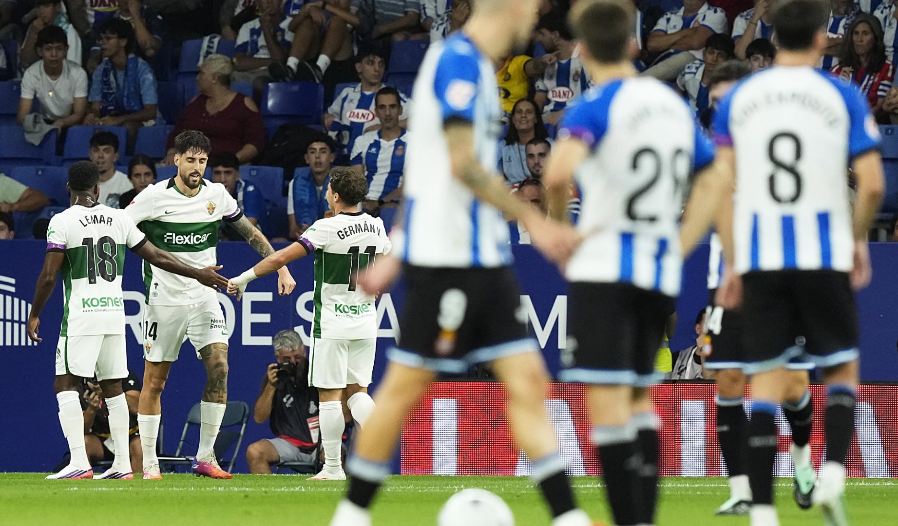 Los jugadores del Elche celebran uno de los dos goles de Fer Niño jugando con uno menos ante la incredulidad de los futbolistas del Espanyol