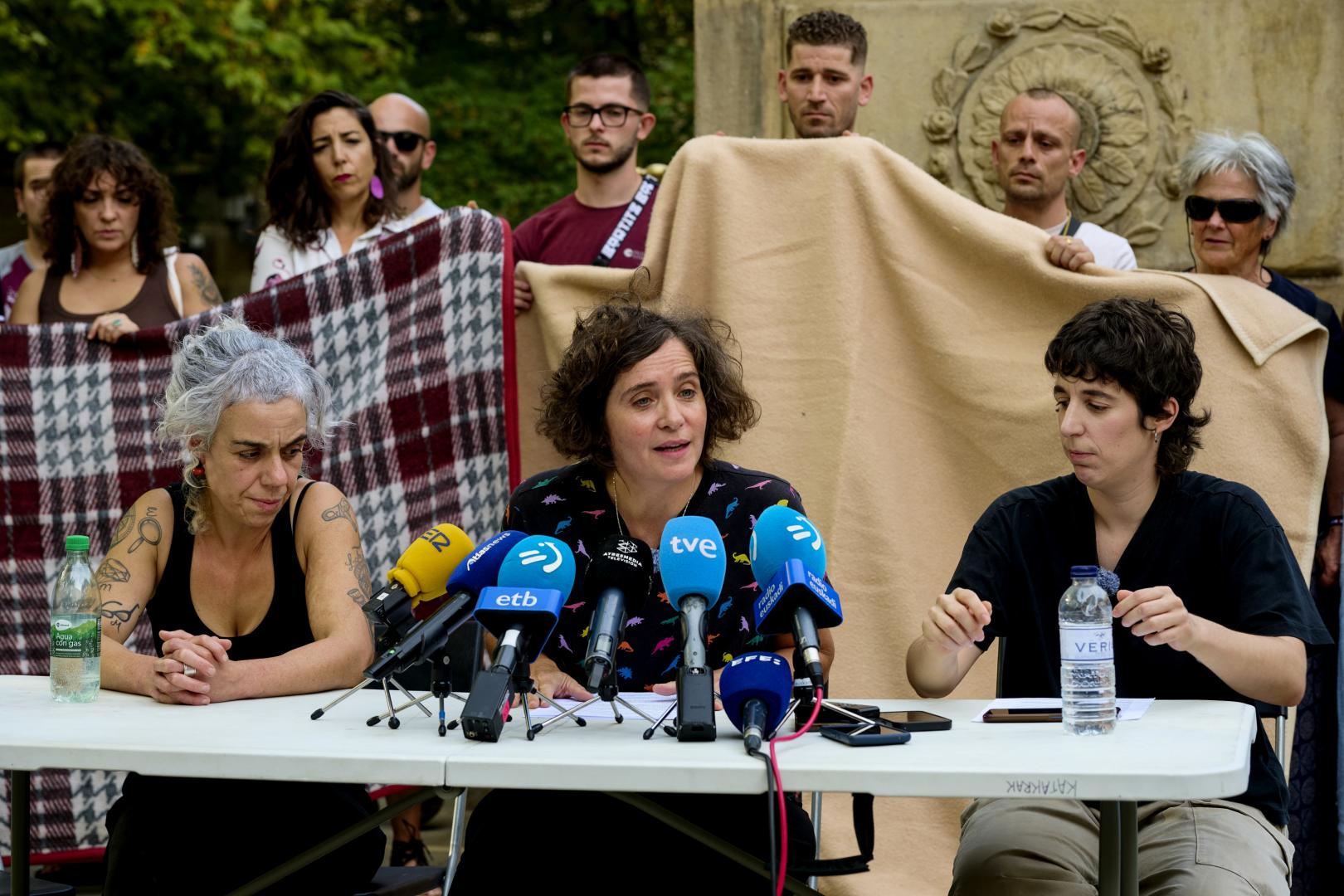 PAMPLONA, 21/09/2026.- El colectivo Derecho a Techo/Negu Gorriak ha denunciado este lunes que integrantes del grupo desplazado desde Pamplona a Ceuta para colaborar con organizaciones que trabajan con personas migrantes han recibido amenazas de muerte y ha hecho un llamamiento a que estos hechos "no hagan que se detenga la solidaridad". Teresa del Romero (c), miembro del colectivo, ha explicado en rueda de prensa que la brigada que partió el domingo forma parte de una iniciativa coordinada con organizaciones que ya trabajan sobre el terreno en Ceuta. EFE/ Iñaki Porto