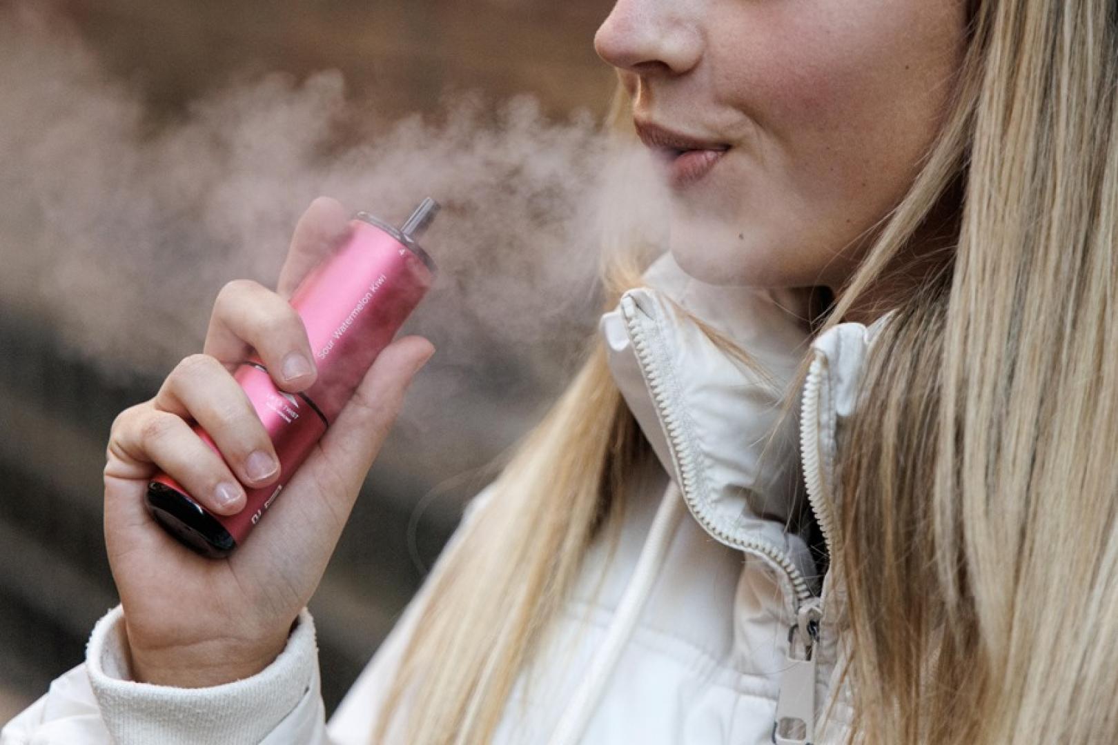Una joven vapea humo con sabor melón y kiwi