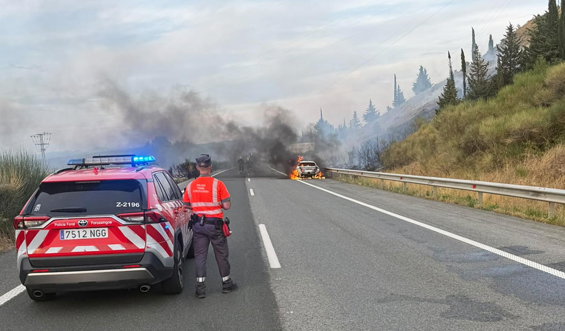 Una patrulla de la Policía Foral junto al coche ardiendo en la AP-15
