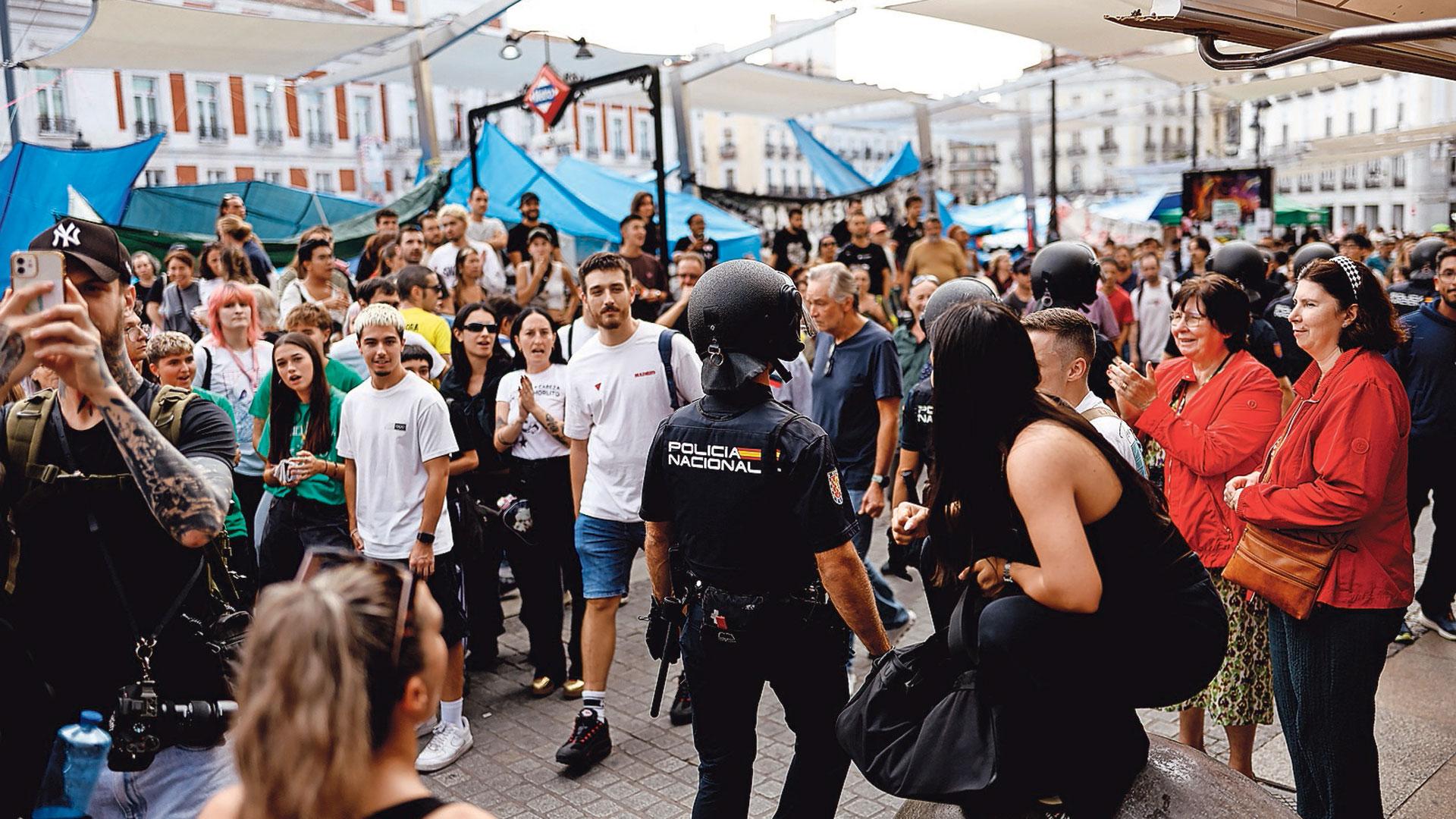 Un agente pasa entre los acampados en Sol, que continuarán la protesta pese al ultimátum de la presidenta de la Comunidad de Madrid