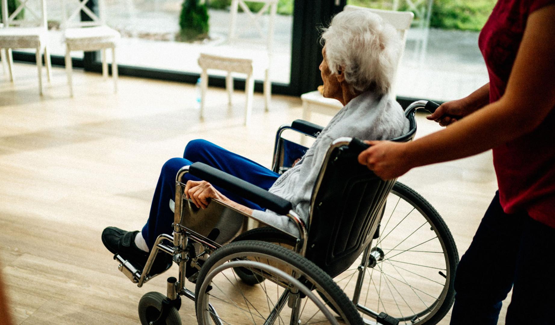 Cuidadora con anciana en silla de ruedas.