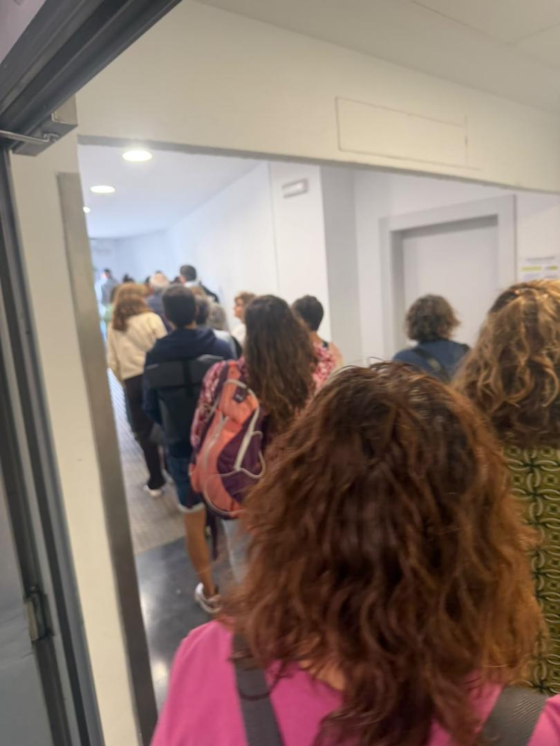 Trabajadores esperando en el HUN para pasar por el reloj de pared y poder fichar.
