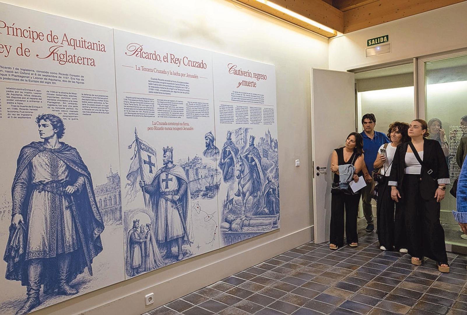 Asistentes a la inauguración observan algunos de los paneles de la muestra.