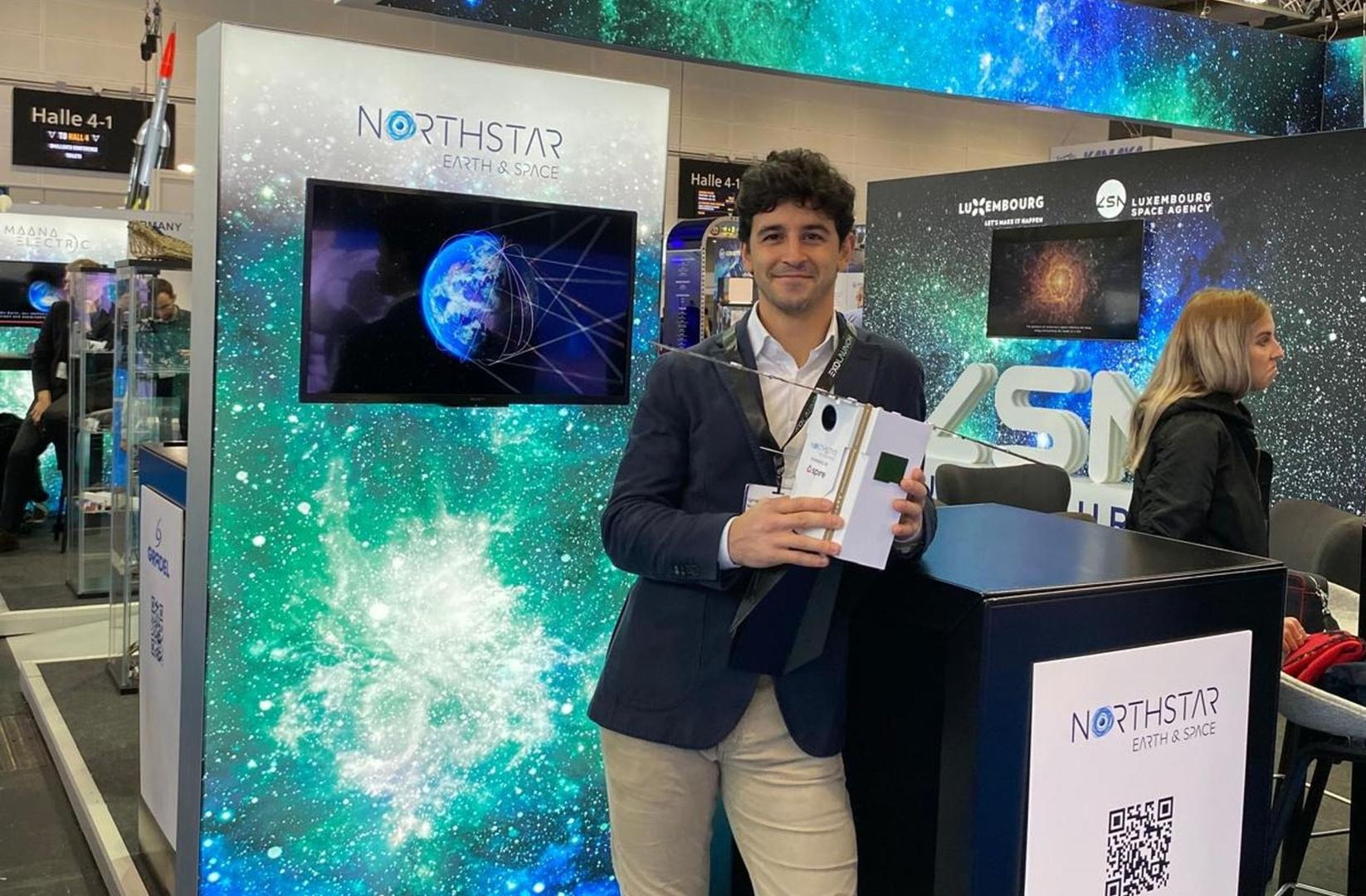 Ignacio Cires de Orbe, en un stand de la empresa, sujeta un modelo de satélite
