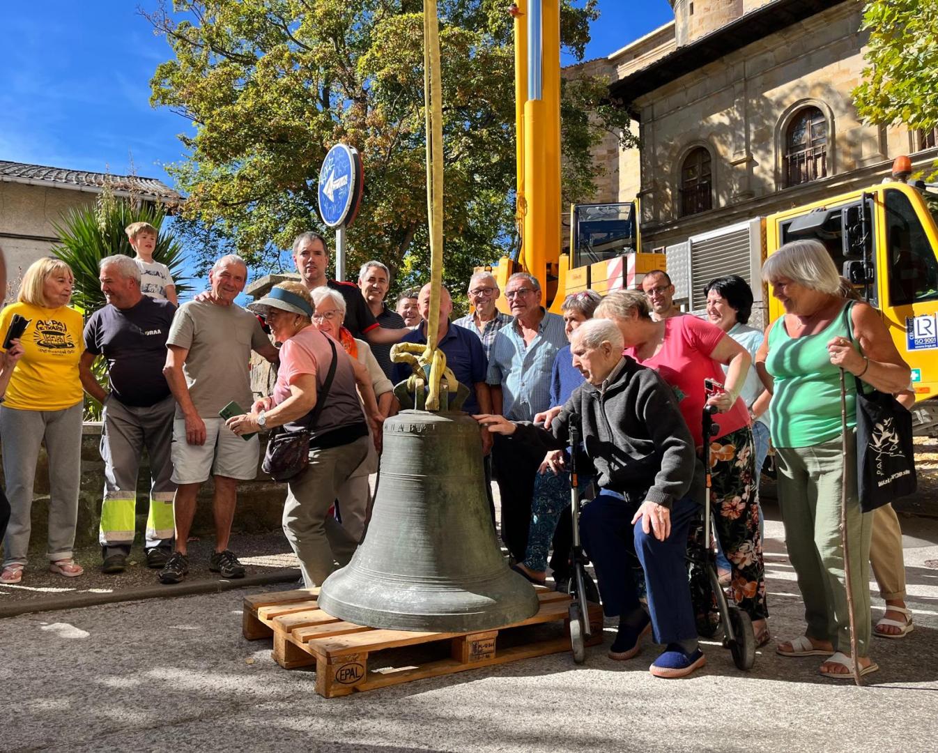 Un grupo de vecinos rodea la campana que será enviada a Austria para eliminar sus fisuras y los daños de un impacto de bala.