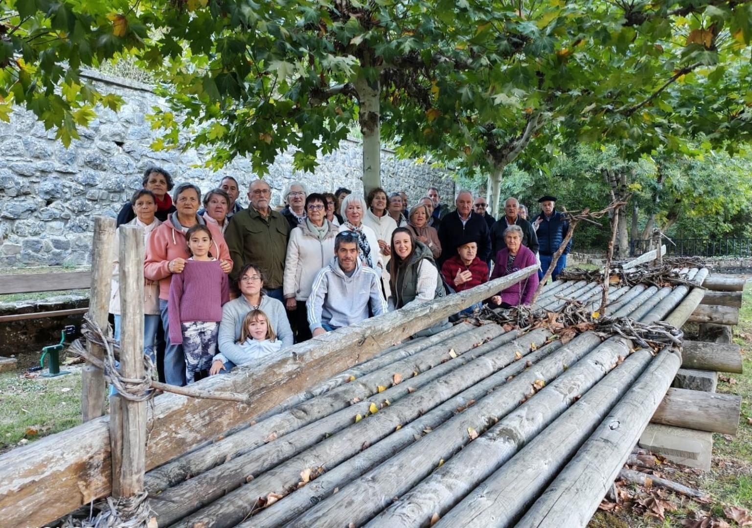Vecinas y vecinos de Ezcároz vinculados al proyecto ‘Camino de agua y cuentos’ posan este viernes junto a la almadía que luce a orillas del río Salazar