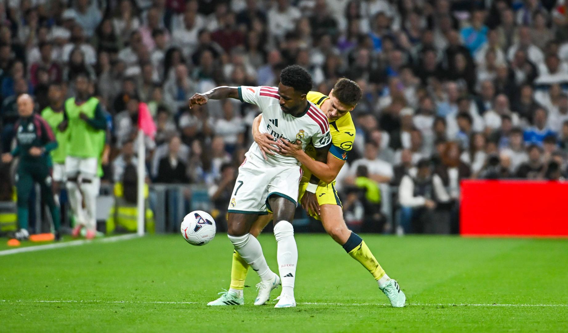 El delantero del Real Madrid Vinicius Jr (delante) lucha por el balón con Juan Foyth (detrás), del Villarreal CF, durante el partido