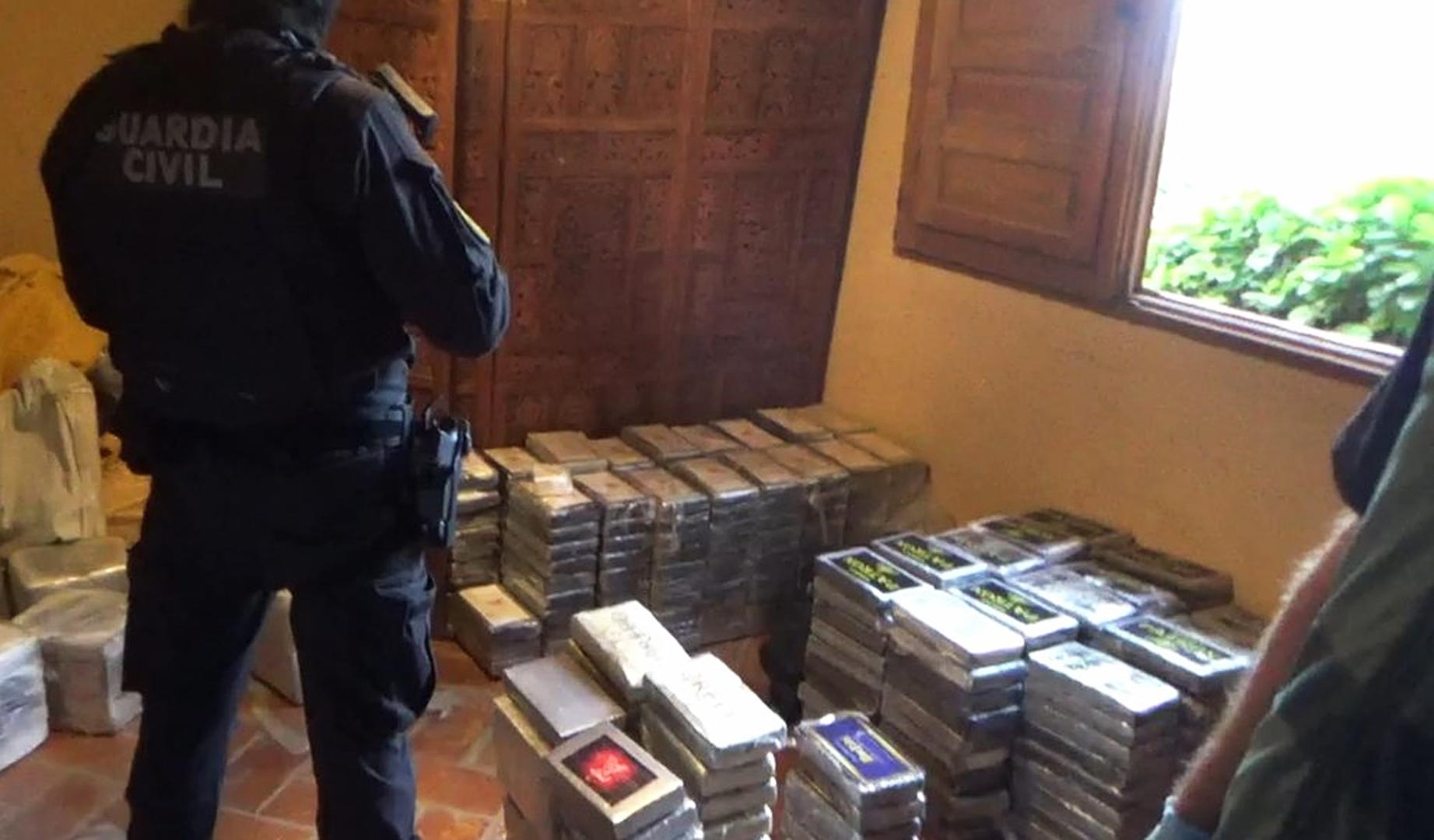 Un agente de la Guardia Civil junto a la droga incautada en la casa rural de Guadalajara
