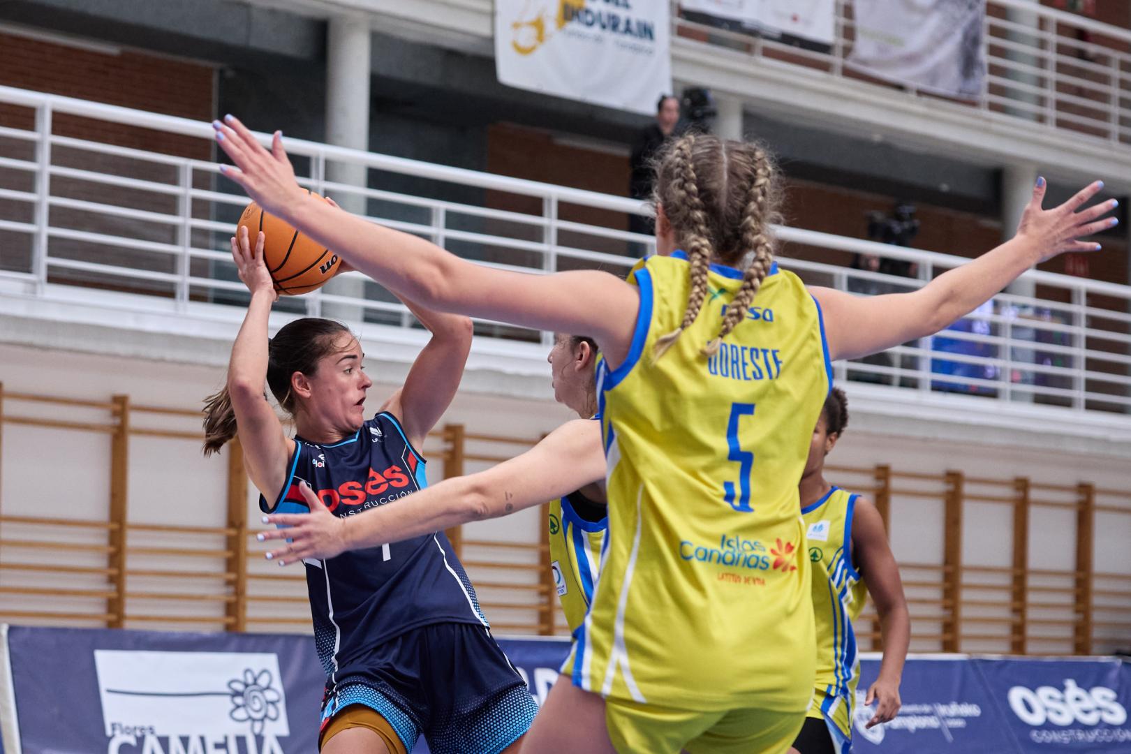 Celia García, nuevo fichaje del Osés Construcción, trata de conceder un pase ante la defensa de dos jugadoras del Spar Gran Canaria