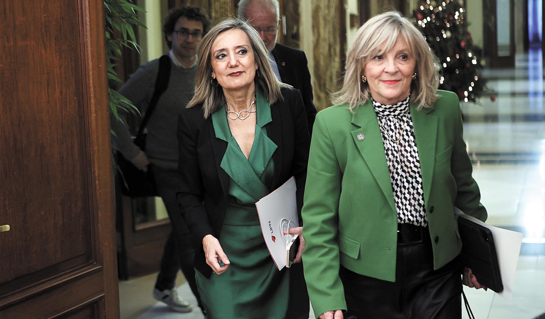 María Caballero y, detrás, Cristina Ibarrola, en una imagen en la que ambas entran a un pleno municipal de Pamplon