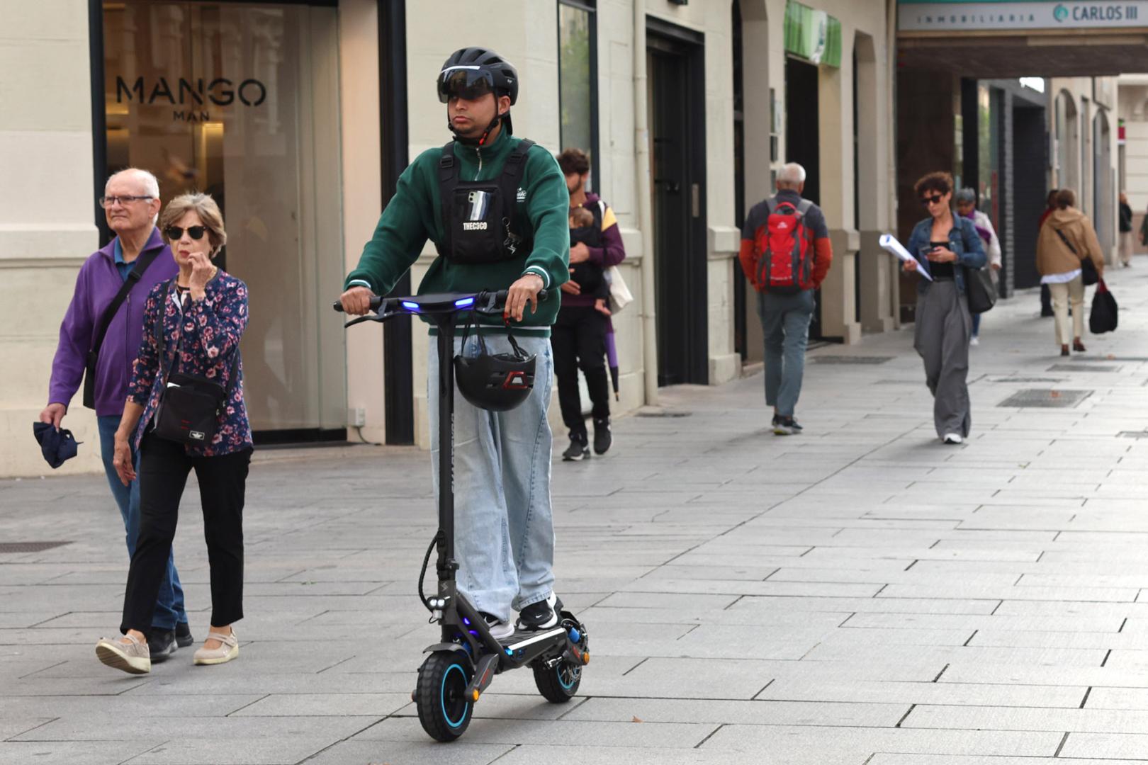 Un joven circula con su patinete eléctrico por una zona peatonal