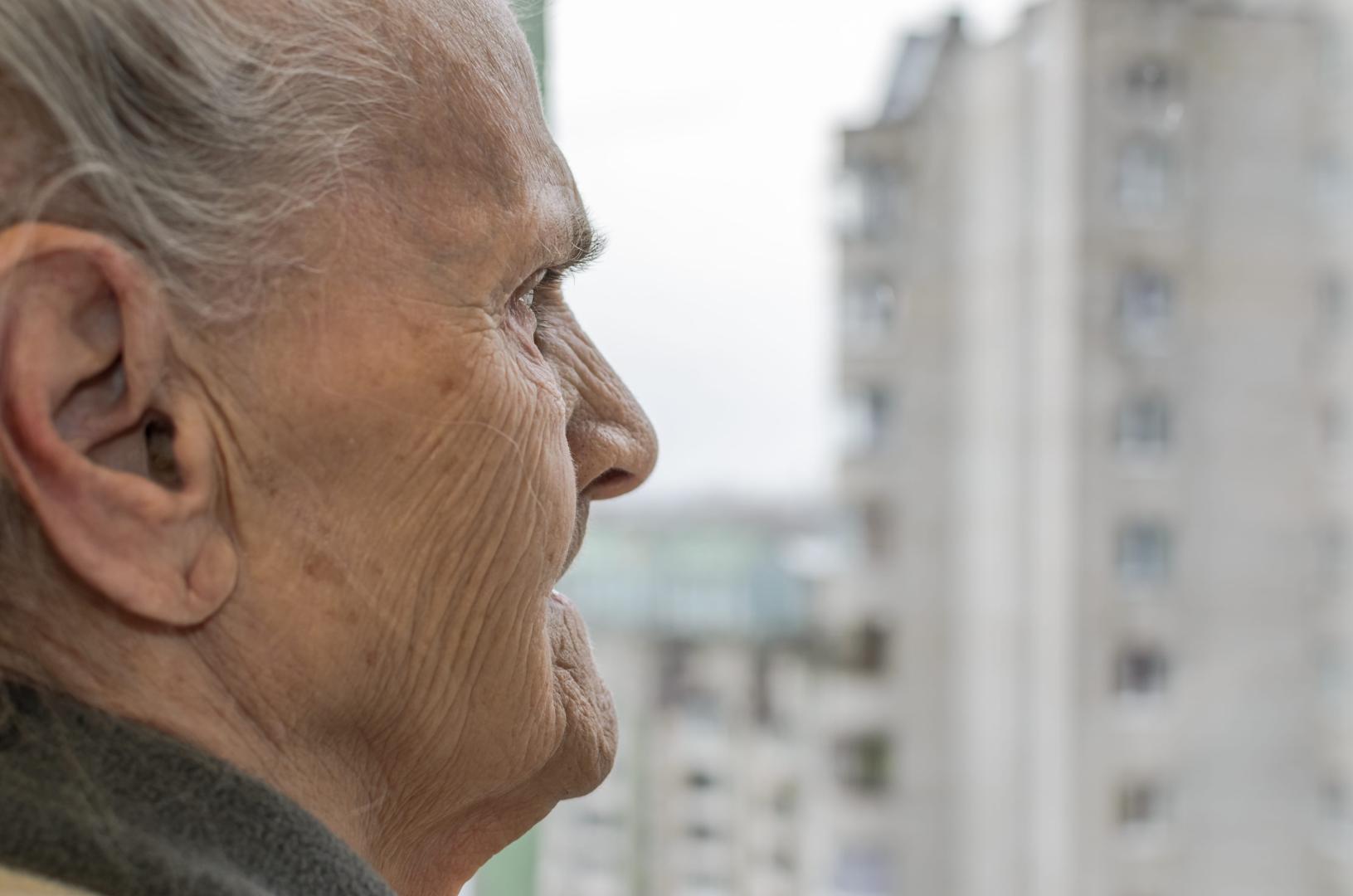 An elderly woman looking out the window