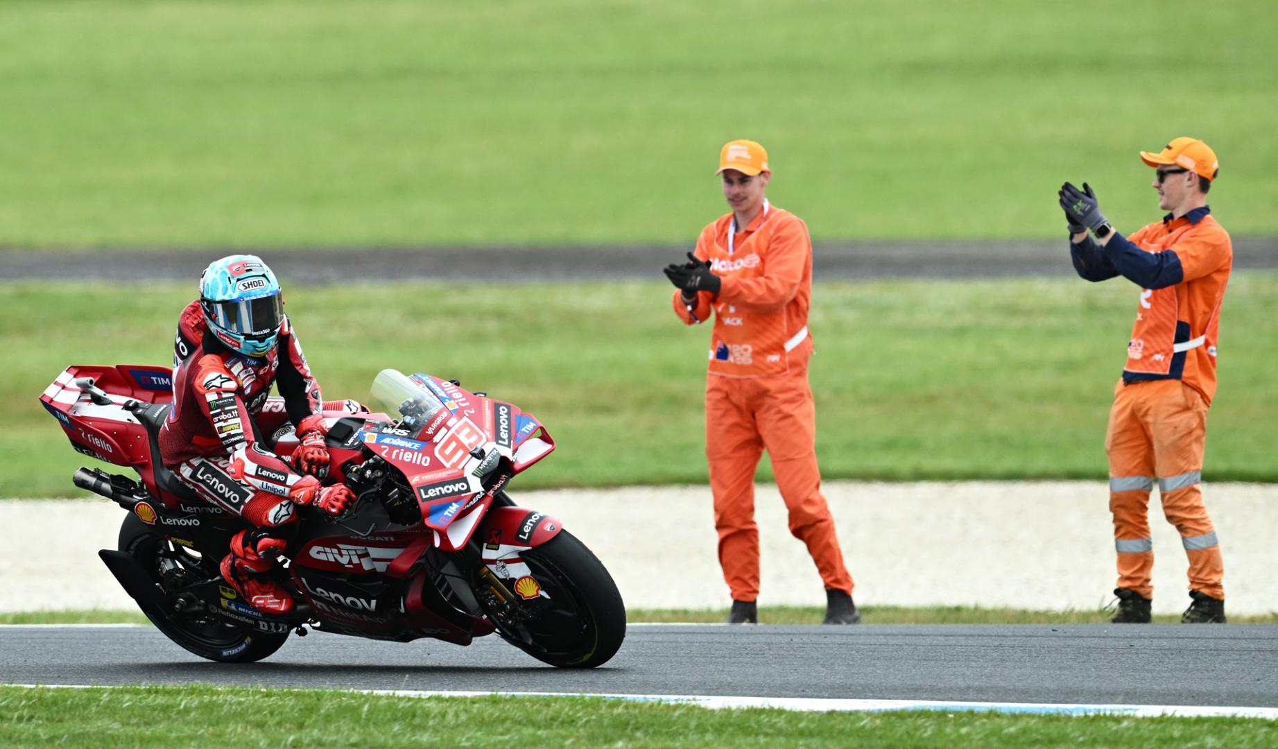 Dos empleados de Phillip Island aplauden a Marc Márquez tras su victoria en la carrera al sprint del GP de Australia