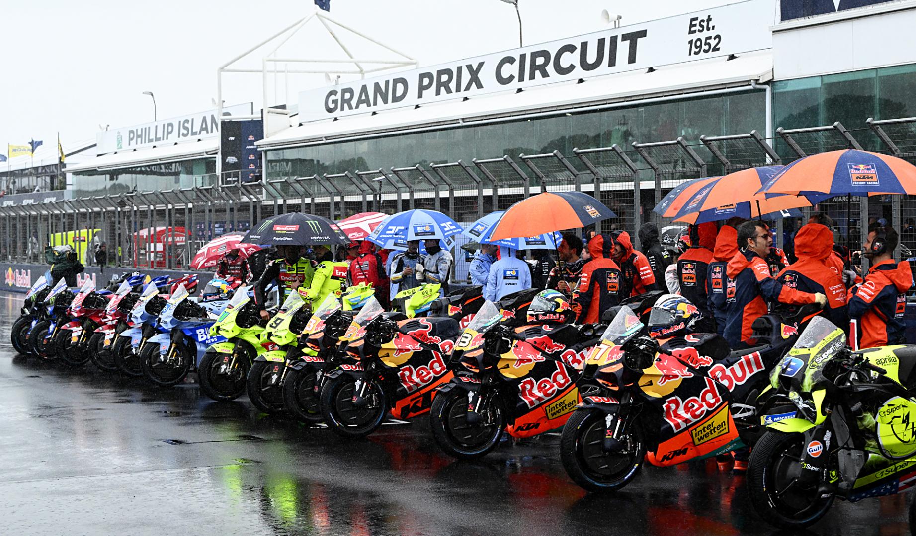 Las motos de MotoGP esperan en la parrilla de salida cubiertas por paraguas antes de la cancelación del GP de Australia en el circuito de Phillip Island