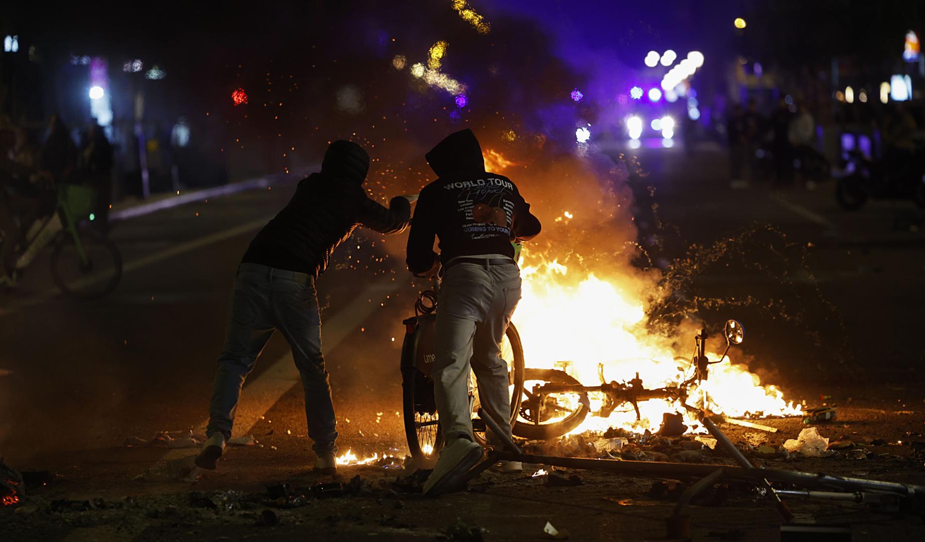 Dos estudiantes alimentan una hoguera durante las protestas de la pasada noche en Barcelona