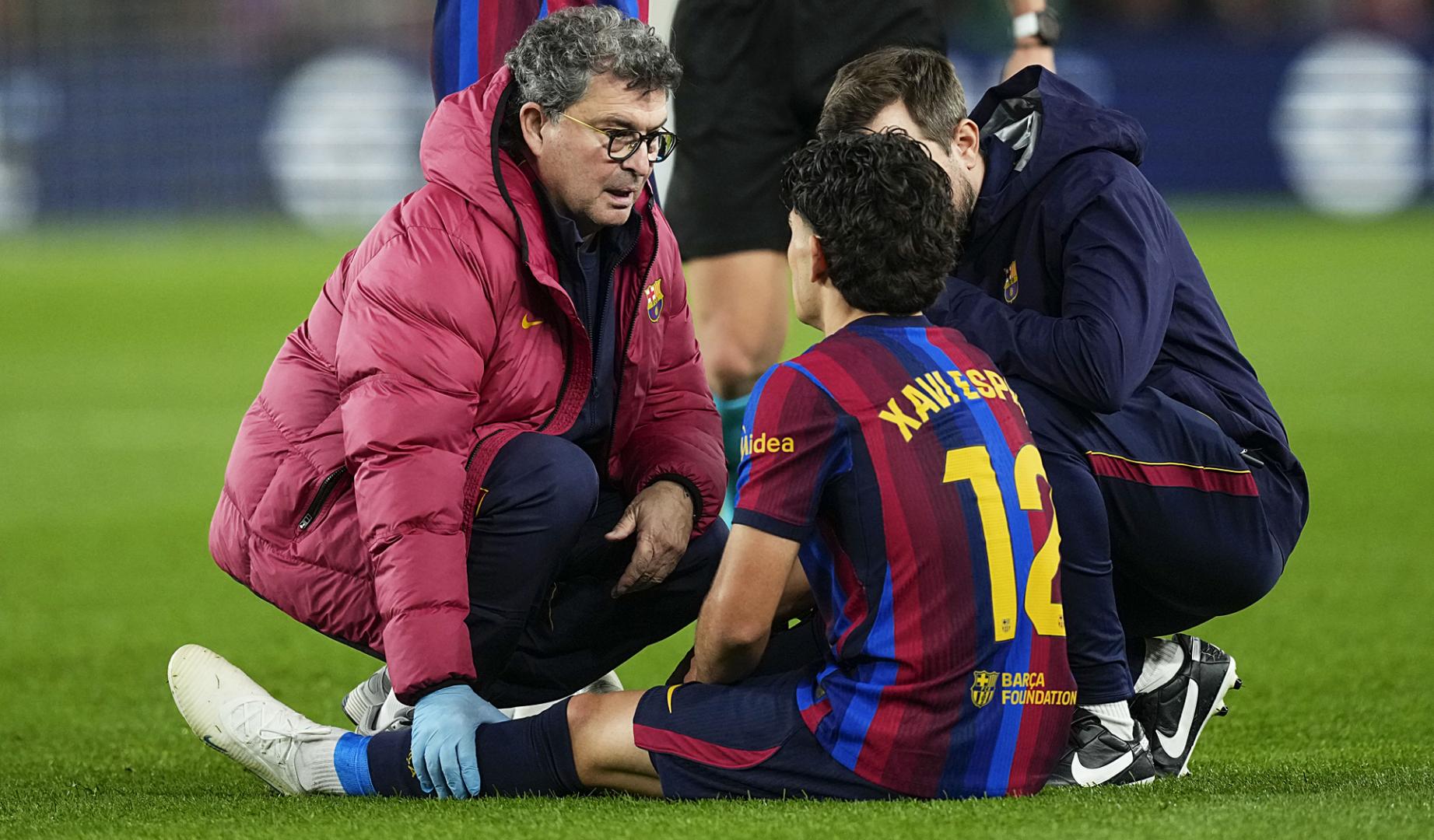 El defensa del Barcelona Xavi Espart recibe atención médica tras lesionarse durante el clásico