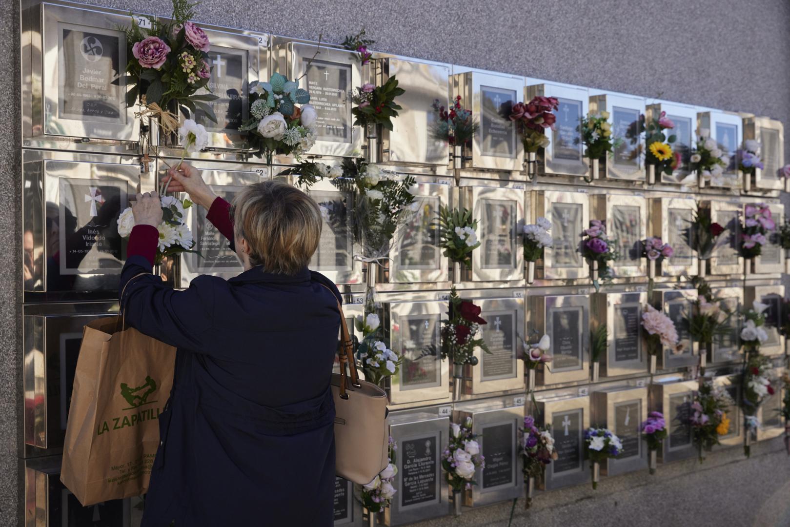 Una persona coloca flores en un columbario del cementerio de Pamplona. Contiene urnas cinerarias y son una opción en auge