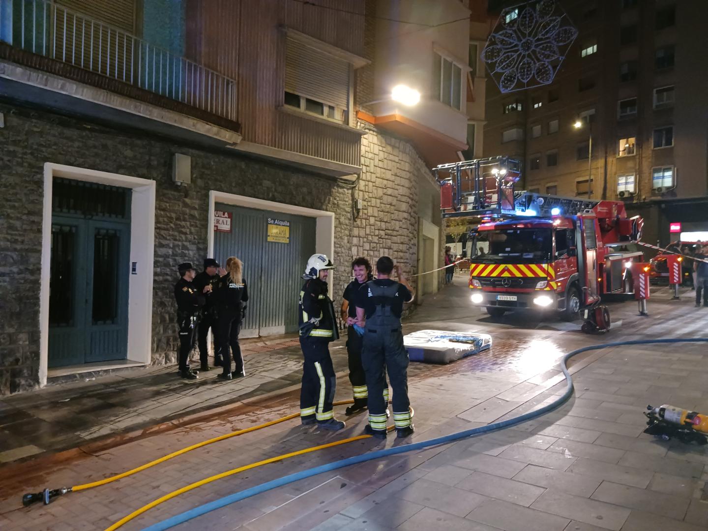Bomberos y policías, en la calle Eza, con el colchón que ardió en el piso y que se lanzó a la calle