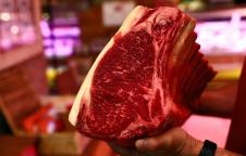 Un carnicero sujeta en la mano una pieza de chuletón Un carnicero sujeta en la mano una pieza de chuletón
