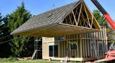 Una grúa coloca el techo de una casa prefabricada Una grúa coloca el techo de una casa prefabricada