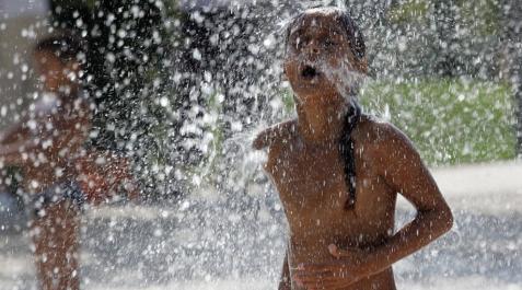 Un niño se refresca durante una ola de calor. Un niño se refresca durante una ola de calor.