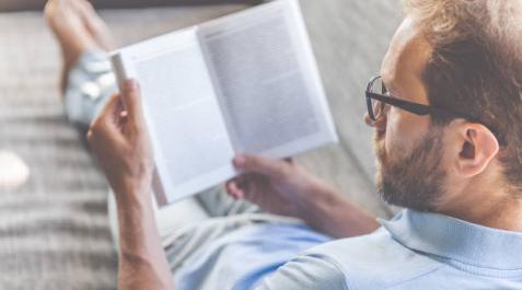 Imagen de un hombre leyendo un libro cómodamente en un sofá Imagen de un hombre leyendo un libro cómodamente en un sofá