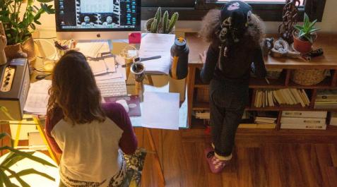 Una mujer realiza teletrabajo en su casa mientras su hija juega a su lado Una mujer realiza teletrabajo en su casa mientras su hija juega a su lado
