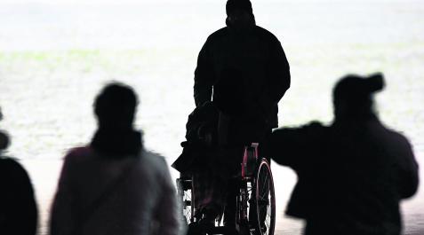 Una persona pasea a otra en silla de ruedas por el centro de Pamplona Una persona pasea a otra en silla de ruedas por el centro de Pamplona