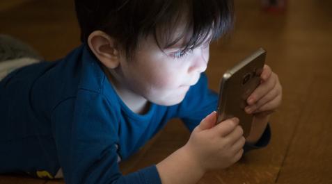 Imagen de archivo de un niño usando un teléfono móvil. Imagen de archivo de un niño usando un teléfono móvil.