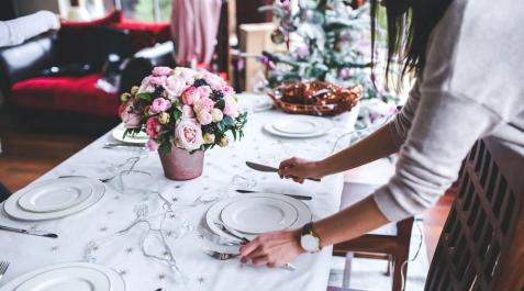 Una mujer prepara la mesa por Navidad Una mujer prepara la mesa por Navidad