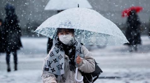 Una mujer con una mascarilla en una calle nevada en Tokio Una mujer con una mascarilla en una calle nevada en Tokio