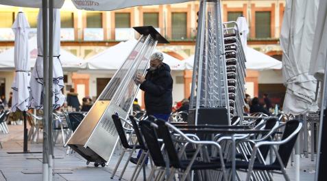 Un empleado retira el mobiliario de una terraza cerrada Un empleado retira el mobiliario de una terraza cerrada