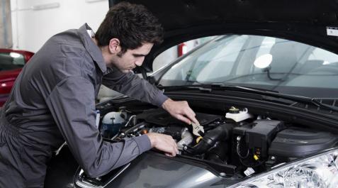 El operario de un taller realiza un trabajo en un coche El operario de un taller realiza un trabajo en un coche