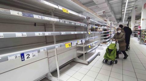 Una mujer observa unas estanterías vacías de legumbres en un supermercado