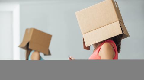 JOVENES-MOVIL Dos jóvenes con el móvil, aisladas del mundo con una caja de cartón en la cabeza
