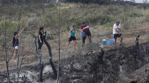 Un grupo de vecinos realiza una cadena con cubos para apagar los rescoldos humenates de una franja de terreno quemada en Muruzábal Un grupo de vecinos realiza una cadena con cubos para apagar los rescoldos humenates de una franja de terreno quemada en Muruzábal