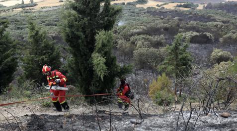 Dos efectivos de la UME (Unidad Militar de Emergencias) suben por la ladera del Perdón con un paisaje, a sus espaldas, entre calcinado y aún sin tocar por el fuego Ladera del Perdón