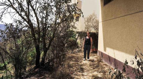 Mª Jesús Janices Valencia, en la parte trasera de su vivienda, con el suelo ennegrecido y la vegetación, sus plantas y flores quemadas. Consiguieron apagar el fuego antes de que alcanzase la fachada Mª Jesús Janices Valencia, en la parte trasera de su vivienda, con el suelo ennegrecido y la vegetación, sus plantas y flores quemadas. Consiguieron apagar el fuego antes de que alcanzase la fachada