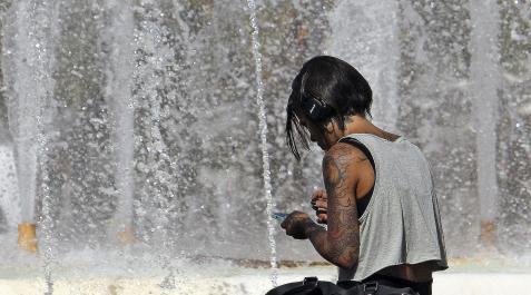 mujer y calor Una mujer trata de refrescarse de las altísimas temperaturas registradas acercándose a los chorros de una fuente urbana. EFE/Morel