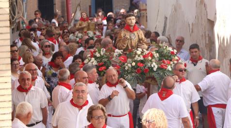 Las imágenes de San Esteban y Santa Bárbara, rodeadas de vecinos durante su desfile procesional Arguedas