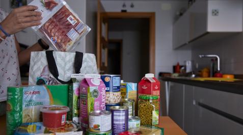 Una persona organiza encima de la mesa de la cocina los alimentos recién adquiridos en el supermercado Una persona organiza encima de la mesa de la cocina los alimentos recién adquiridos en el supermercado
