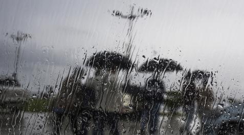 Lluvias Varias personas se protegen con un paraguas de la lluvia que empaña un cristal