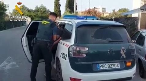 Alicante Un agente de la Guardia Civil mete en el coche patrulla a uno de los detenidos