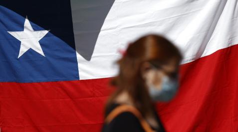 chile-constitucion Una mujer camina frente a una bandera de Chile